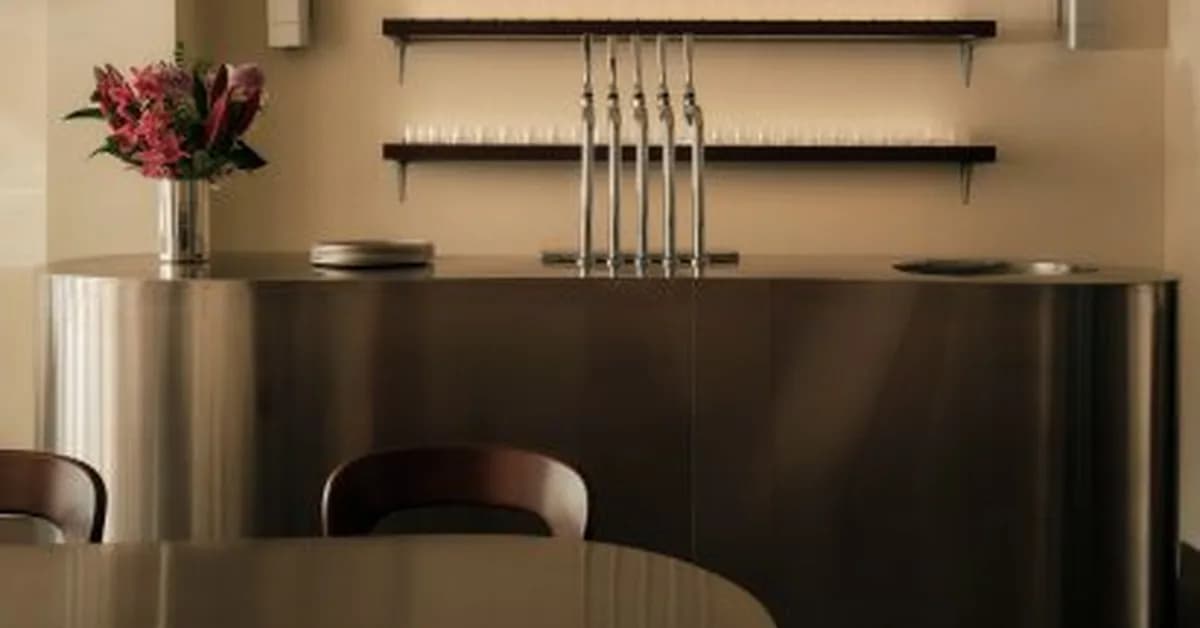 Curving communal table forms "archipelago of steel" at centre of Kiez Kebab restaurant